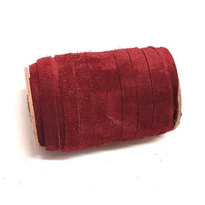 May include: A roll of burgundy suede leather cord. The cord is wrapped around a cardboard tube.