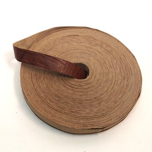 Może przedstawiać: Rolka brązowego sznurka skórzanego, owinięta wokół siebie, z brązowym skórzanym paskiem trzymającym ją razem.