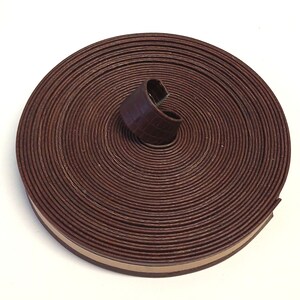 May include: A roll of brown leather trim with a beige edge. The leather is textured and has a crocodile pattern.
