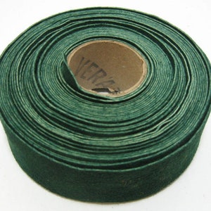 Könnte beinhalten: Eine Rolle dunkelgrünes Stoffband, um einen Pappkern gewickelt. Der Kern trägt die Aufschrift "VERA".