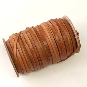 May include: A spool of brown leather cord, wound tightly and ready for crafting projects.