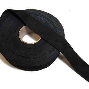 Könnte beinhalten: Eine Rolle schwarzes Schrägband, eine Art Stoffbesatz, der zum Verarbeiten von Kanten an Kleidungsstücken und anderen Nähprojekten verwendet wird.