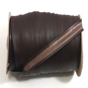 May include: A roll of brown leather trim with a thin, light brown stripe down the centre.