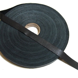May include: A roll of black leather cord, wound around itself. The cord is about 1/2 inch wide.