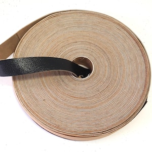 Może przedstawiać: Rolka brązowego sznurka skórzanego z przymocowaną czarną skórzaną taśmą. Sznurek jest zwinięty w kółko, a taśma owinięta wokół zewnętrznej strony rolki.