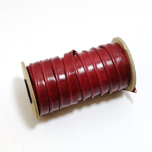 May include: A roll of red leather cord, wound around a cardboard spool.