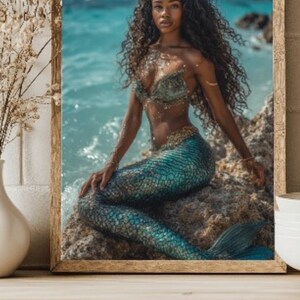 May include: A framed print of a mermaid sitting on a rock near the ocean. The mermaid has long, curly black hair, a teal and gold seashell top, and a teal and gold scaled tail. The background shows the ocean and sky.