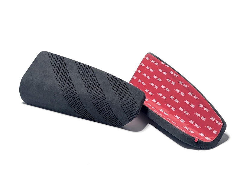 May include: Two black, curved automotive accessories. One has a perforated surface, the other has a red adhesive backing with white text. The accessories are designed to be attached to a vehicle.