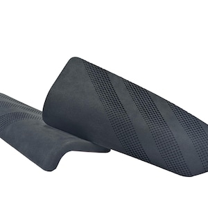 May include: Two dark gray shin guards with a textured surface and diagonal striped pattern. The guards are made of a flexible material and are designed to protect the lower legs during sports activities. The guards are shown against a white background.