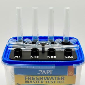 May include: A freshwater master test kit with clear test tubes, droppers, and a black platform labeled PH, NH3, NO2, and NO3. The kit is in a blue and clear plastic container.