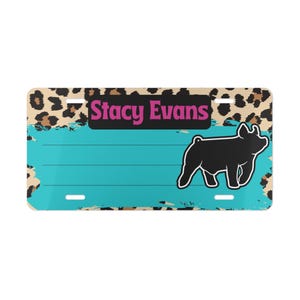 May include: Rectangular license plate with a turquoise background and a black pig silhouette. The top border features a leopard print design. The text "Stacy Evans" is in pink letters on a black background.