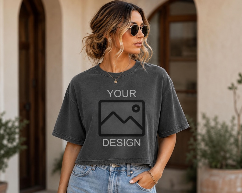 May include: A charcoal gray cropped t-shirt featuring a black graphic of a mountain landscape inside a rectangular frame with the text YOUR above and DESIGN below the graphic. The shirt has short sleeves and a crew neckline.