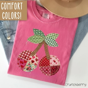 May include: A white ceramic mug with a black handle and the text "But First, Coffee" in a black, handwritten-style font. The mug is on a white surface.