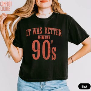 May include: A black short-sleeved t-shirt featuring the red distressed text "IT WAS BETTER IN THE 90's" printed on the front. The shirt has a crew neckline and a standard fit. The text is centred on the chest in a bold, vintage-style font.