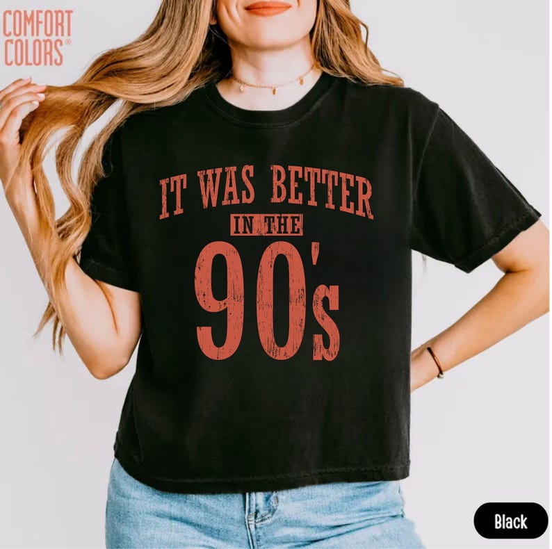 May include: A black short-sleeved t-shirt featuring the red distressed text "IT WAS BETTER IN THE 90's" printed on the front. The shirt has a crew neckline and a standard fit. The text is centred on the chest in a bold, vintage-style font.