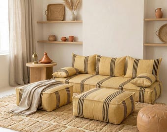 May include: A yellow sofa and matching ottomans with black vertical stripes. The sofa has several throw pillows with the same striped pattern. The furniture sits on a textured, light brown rug, creating a cohesive living room set.