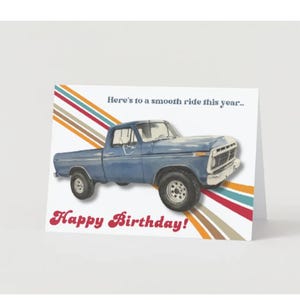 May include: Greeting card with a blue pickup truck illustration. The card has the text "Here's to a smooth ride this year..." and "Happy Birthday!" in a retro font. Colorful diagonal stripes accent the design.