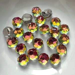 May include: A collection of iridescent glass beads in a variety of colors, including red, orange, yellow, green, blue, and purple. The beads are round and have a faceted surface. They are arranged in a bowl.