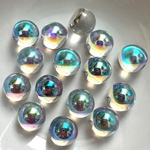 May include: A collection of iridescent glass marbles in various shades of blue and green, with a single white marble in the center.