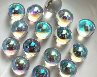 Könnte beinhalten: Eine Sammlung von regenbogenfarbenen Glasmurmeln in verschiedenen Blautönen und Grüntönen, mit einer einzelnen weißen Murmel in der Mitte.