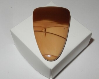 May include: A brown and tan agate cabochon with a triangular shape. The stone has a layered pattern with brown, tan, and white colors.