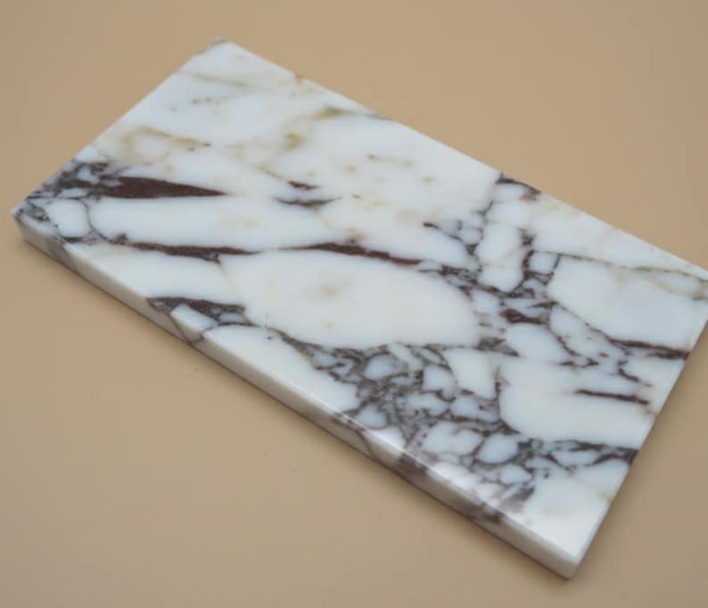 May include: A rectangular marble slab with a white base and dark brown veining. The polished surface has a natural stone pattern. The slab is likely used for decorative or functional purposes, such as a cutting board or serving tray.