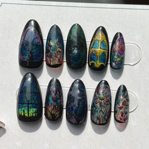 May include: A set of ten press-on nails with a glossy finish. Each nail features a unique design with dark backgrounds and colourful floral or stained-glass window patterns. The nails are displayed on a white card with the "Nuli beauty" logo.