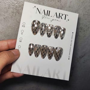 Könnte beinhalten: Ein Set silberner, verspiegelter Nagelkunst, präsentiert auf einer weißen Karte. Die mandelförmigen Nägel weisen ein Mosaikdesign auf. Die Karte zeigt "NAIL ART for you" und Größenoptionen.