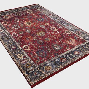 K&ouml;nnte beinhalten: Ein rechteckiger Teppich mit traditionellem Design. Der Teppich hat ein tiefrotes Mittelfeld mit floralen und geometrischen Mustern in Blau, Beige und Gold. Ein dunkelblauer Rand umrahmt das Design.