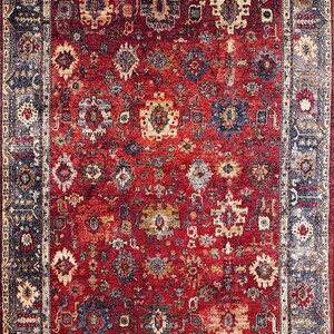 K&ouml;nnte beinhalten: Ein rechteckiger Teppich mit traditionellem Design. Der Teppich hat ein tiefrotes Mittelfeld mit komplizierten Mustern in Blau, Beige und Gold. Ein dunkelblauer Rand rahmt das Design ein und verleiht der Gesamt&auml;sthetik Kontrast und Definition. Geeignet f&uuml;r Wohnzimmer.