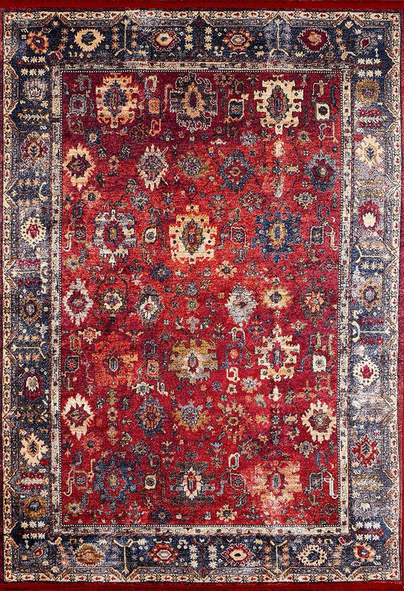 K&ouml;nnte beinhalten: Ein rechteckiger Teppich mit traditionellem Design. Der Teppich hat ein tiefrotes Mittelfeld mit komplizierten Mustern in Blau, Beige und Gold. Ein dunkelblauer Rand rahmt das Design ein und verleiht der Gesamt&auml;sthetik Kontrast und Definition. Geeignet f&uuml;r Wohnzimmer.