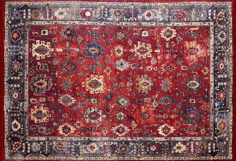 K&ouml;nnte beinhalten: Ein rechteckiger Teppich mit einem roten Mittelfeld und einem detaillierten Rand. Der Teppich weist ein sich wiederholendes Muster aus floralen und geometrischen Designs in Blau-, Creme- und Goldt&ouml;nen auf. Der Rand ist dunkelblau mit Creme- und Goldakzenten.