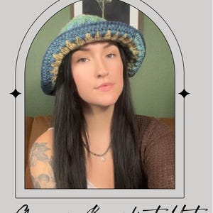 Puede incluir: Sombrero de cubo granny hecho a mano en tonos azules, verdes y beige. El sombrero está tejido a ganchillo con un punto texturizado y tiene una copa redondeada y un ala ligeramente acampanada. El texto "Granny Bucket Hat" está escrito en cursiva en la parte inferior.