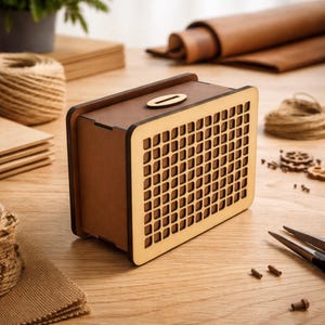 Può includere: Un salvadanaio rettangolare in legno con una fessura sulla parte superiore. La scatola ha un corpo marrone e un fronte chiaro a motivo a griglia. Il design è semplice e moderno, adatto a un elemento di arredo per la casa, lungo circa 15 cm.