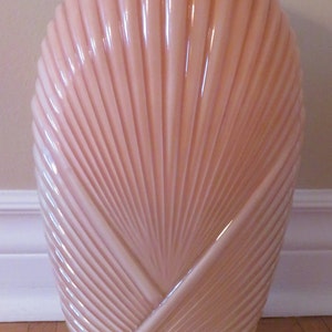 以下が含まれることがあります： 扇形のデザインが施された薄いピンク色のガラスの花瓶。花瓶は虹色のガラスでできており、滑らかで光沢のある仕上がりです。