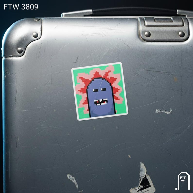 Puede incluir: Una pegatina cuadrada con una criatura azul pixelada con un dise&ntilde;o espinoso rojo y rosa sobre un fondo verde. La pegatina est&aacute; adherida a una maleta plateada. El texto "FTW 3809" est&aacute; en la esquina superior izquierda.