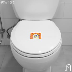 Puede incluir: Un inodoro blanco con una pegatina en la tapa. La pegatina presenta un personaje de dibujos animados pixelado con una cara beige, ojos azules y un bigote morado, sobre un fondo naranja y rosa. El texto "FTW 1082" est&aacute; en la esquina superior izquierda.