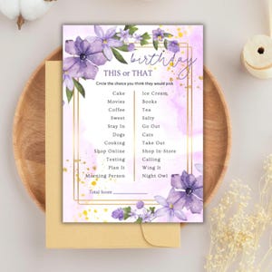 May include: A party game card with the text "THIS or THAT" and "birthday" in a decorative font. The card features a floral design with purple flowers and gold accents. The game lists various choices for players to select.