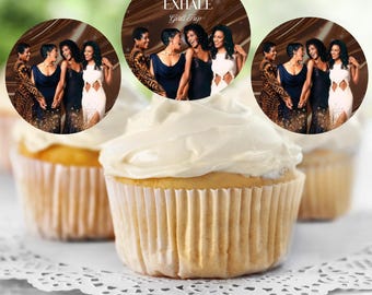 Könnte beinhalten: Cupcakes mit weißem Zuckerguss und essbaren Auflegern mit dem Text "WAITING TO EXHALE Girls Trip" und einem Bild von fünf Frauen. Die Cupcakes stehen auf einer weißen, spitzenartigen Unterlage.
