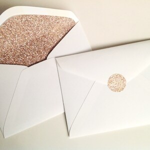 May include: White envelopes, one open to show a rose gold glitter lining, the other sealed with a matching round sticker. The envelopes are suitable for invitations or special announcements. The glitter adds a touch of elegance.