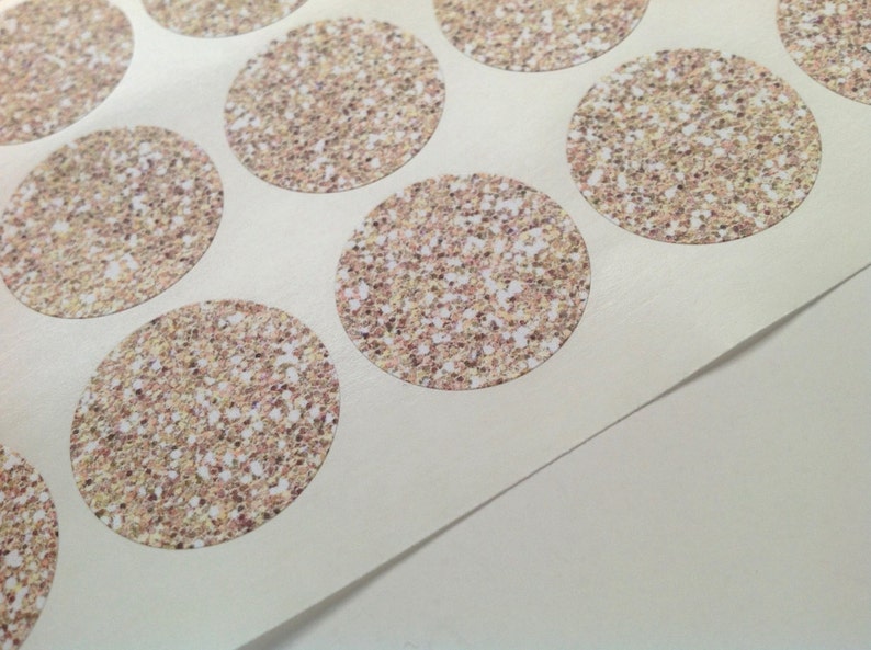 May include: Sheet of round stickers with a glittery, speckled design in shades of gold, brown, and white. The stickers are arranged in a grid pattern on a white backing.