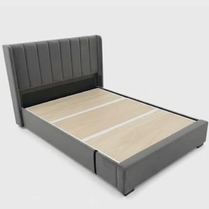 May include: A grey upholstered bed frame with a vertical-panelled headboard. The bed frame has a wooden base and a low profile. The bed frame is designed for a modern bedroom.