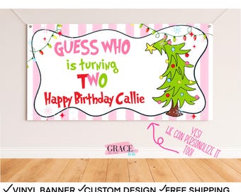 May include: A custom birthday banner with a pink and white striped background. The banner reads "Guess Who is turning TWO Happy Birthday Callie" with a green Christmas tree graphic. The banner is designed for a birthday celebration.