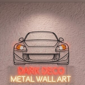 May include: Metal wall art featuring a car outline with illuminated headlights. The neon sign below reads "DARK DECO METAL WALL ART". The artwork is mounted on a textured wall.