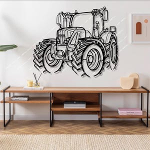 Könnte beinhalten: Schwarze Wandkunst aus Metall, die einen Traktor mit großen Rädern darstellt. Der Traktor ist an einer weißen Wand über einem Holzregal mit schwarzen Metallbeinen montiert. Das Regal enthält Bücher und Dekorationsartikel.