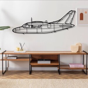 May include: A black metal airplane wall decor with a wood shelf unit with black metal legs and shelves. The shelf unit has books and decorative items on it.