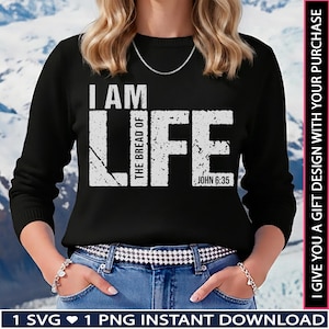 Puede incluir: Sudadera negra de manga larga con la frase "I AM LIFE" en letras blancas desgastadas. La frase "THE BREAD OF" está apilada verticalmente entre "I AM" y "LIFE". La referencia bíblica "JOHN 6:35" está debajo de "LIFE".