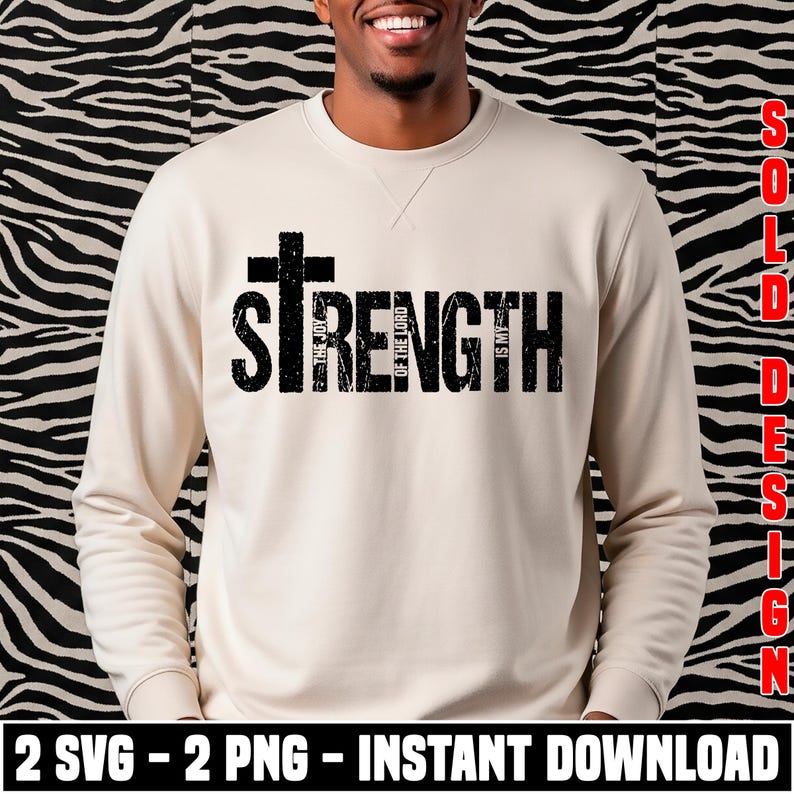 K&ouml;nnte beinhalten: Ein beiges Sweatshirt mit dem Wort "STRENGTH" in gro&szlig;en, verwaschenen schwarzen Buchstaben und einem Kreuz &uuml;ber dem Wort. Der Text "THE JOY OF THE LORD IS MY" ist vertikal in dem Wort "STRENGTH" abgedruckt. Der untere Teil des Bildes enth&auml;lt den Text "2 SVG - 2 PNG - INSTANT DOWNLOAD".
