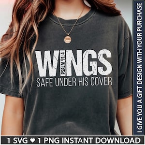 Puede incluir: Una camiseta de manga corta gris carbón con texto blanco desgastado que dice WINGS PSALM 91:4 SAFE UNDER HIS COVER. La prenda tiene cuello redondo y un ajuste relajado, acompañada de un collar de cadena dorada fina con un colgante redondo.