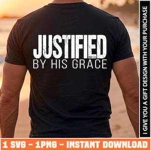 Puede incluir: Una camiseta negra de manga corta con texto blanco desgastado en la espalda que dice JUSTIFIED BY HIS GRACE, con el texto más pequeño ROM 3:24 situado debajo de la palabra JUSTIFIED en una fuente sans-serif clara.